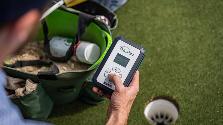 A golfer holding the PACE systems TruPin device.