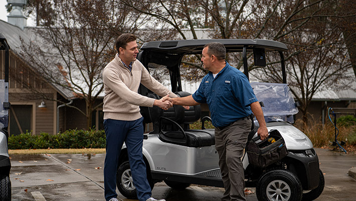 Two men shaking hands in front of an E-Z-GO vehicle